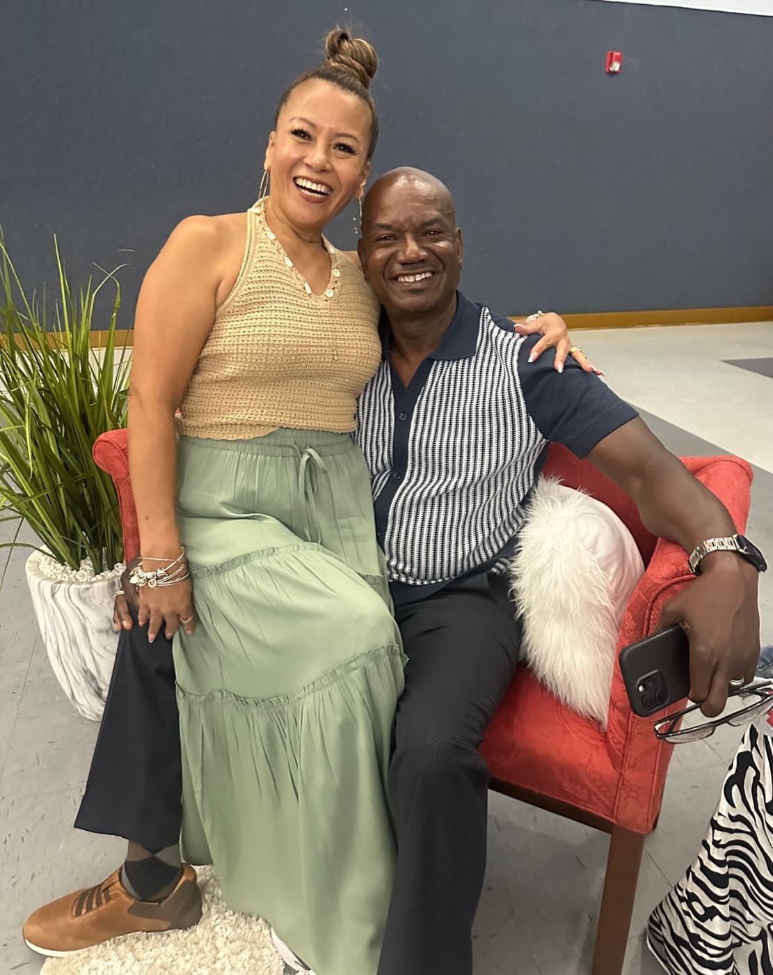 CIC couple sharing a joyful moment in the red chair photo setup.