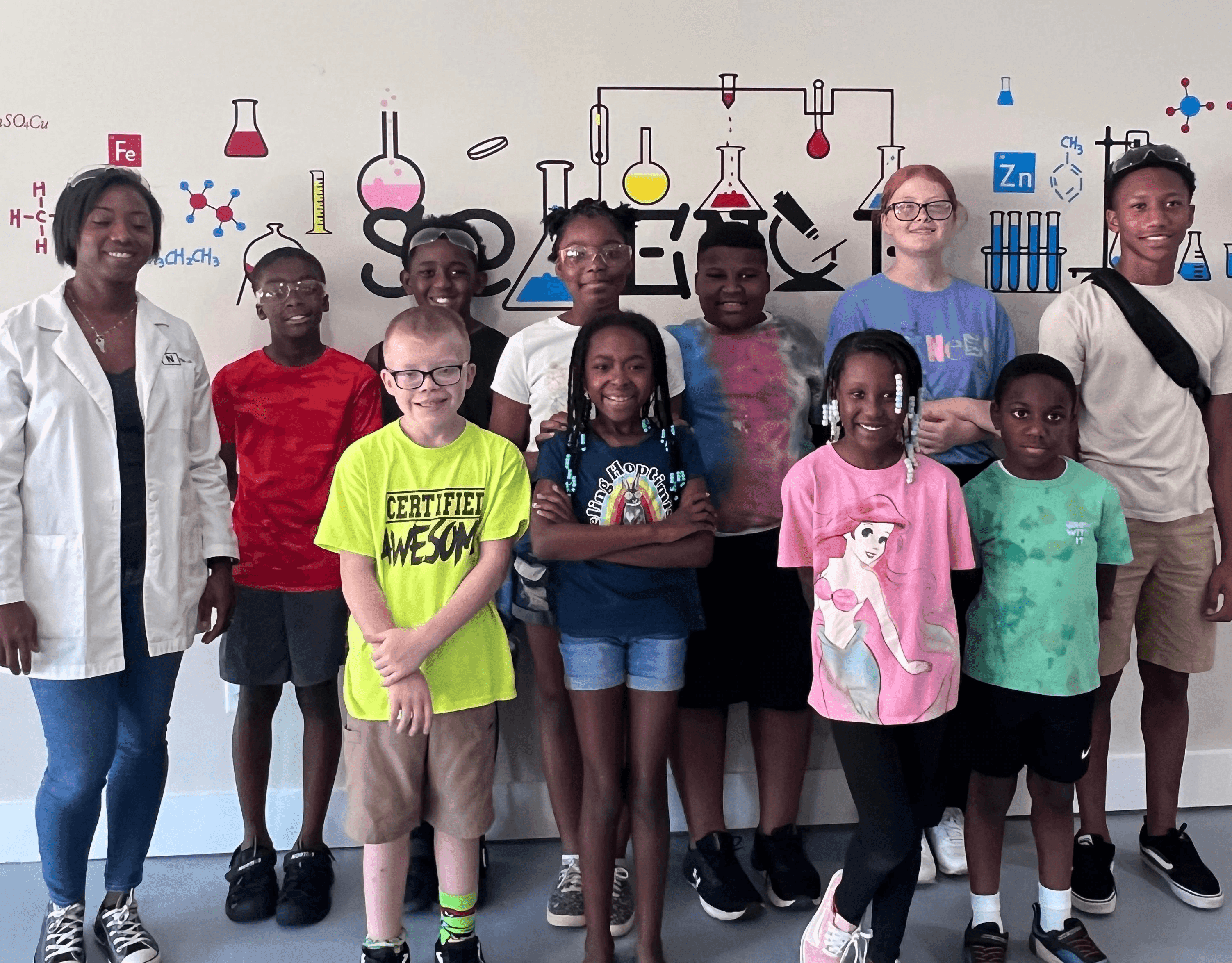 Children smiling during youth programming with a science-themed backdrop.